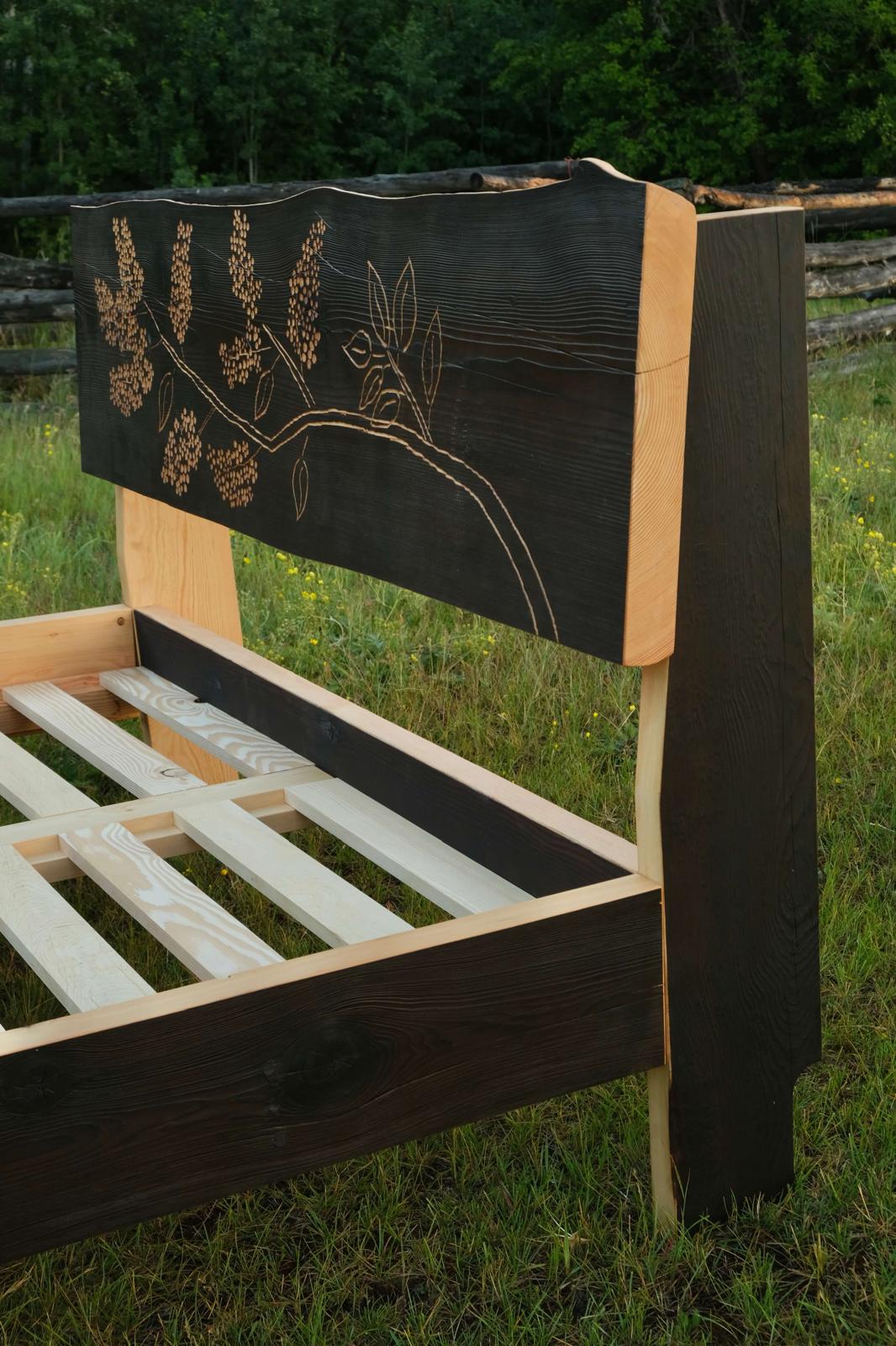 Hand-carved headboard on the Lilac bed frame, with lilac flowers and stems carved into fire-charred Douglas fir